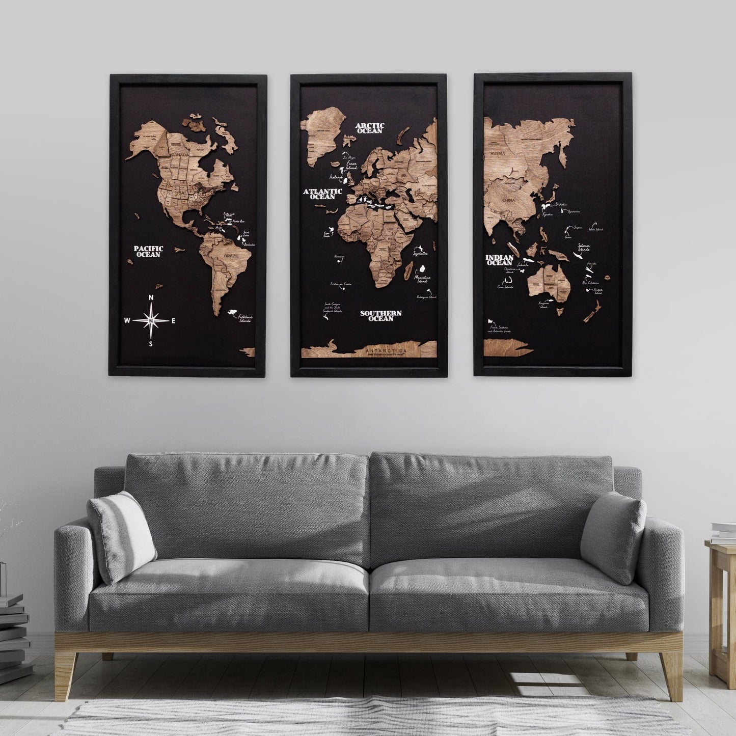 Three framed world maps above a gray sofa in a living room.
