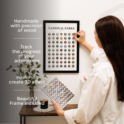 Woman hanging a framed National Parks travel map with push pins on a wall.