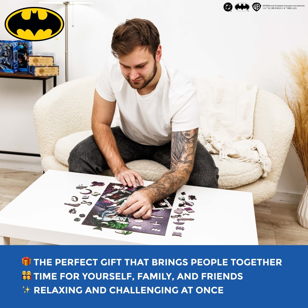 Man assembling a puzzle on a coffee table with Batman logo in the corner