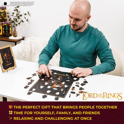 Man assembling a 'The Lord of the Rings' themed puzzle on a table.