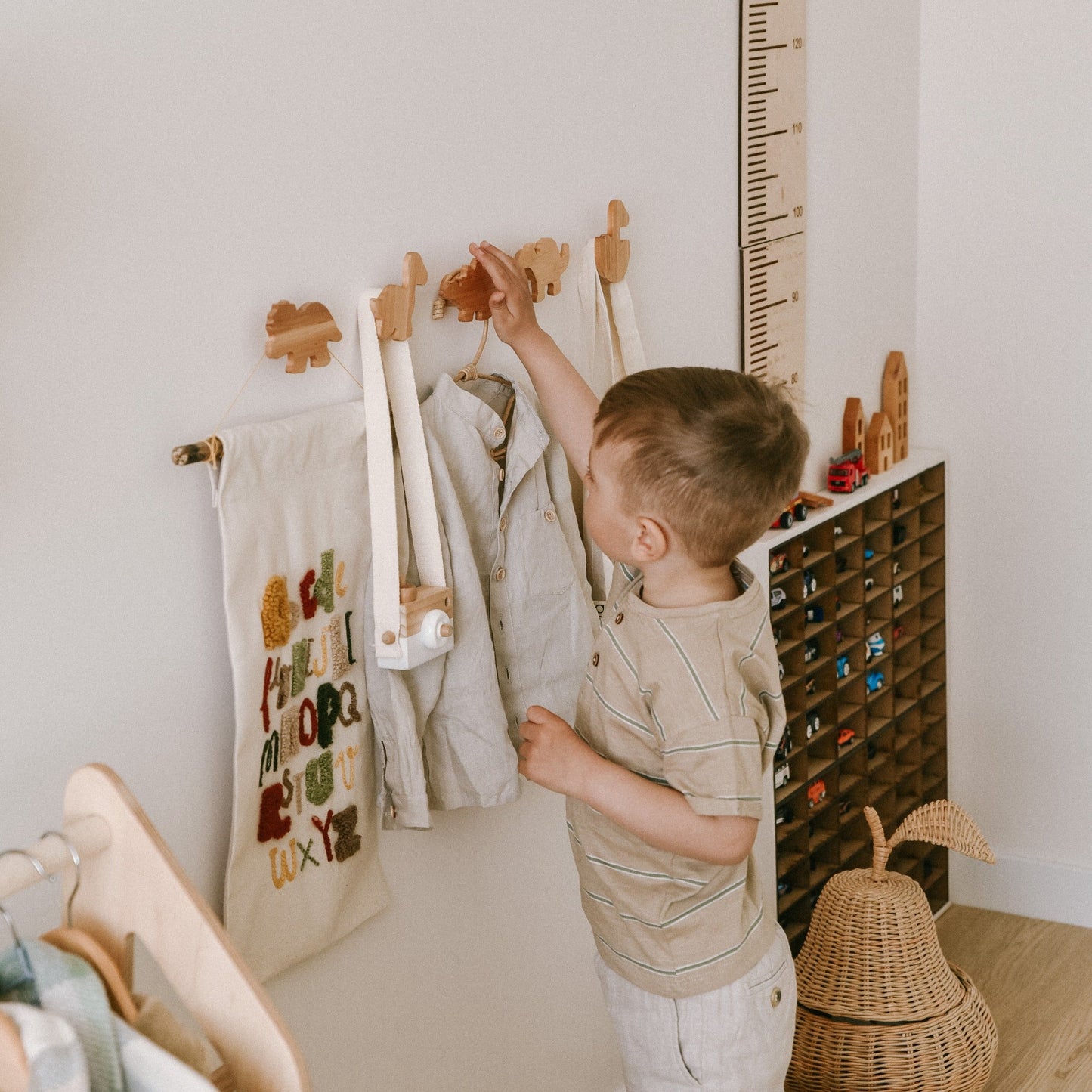 Child playing with a toy in a room with educational items on the wall.