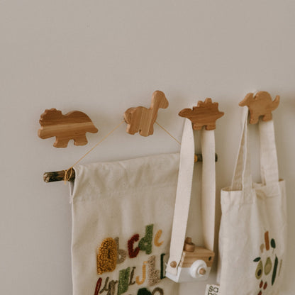 Wooden animal-shaped hooks on a wall with hanging bags.