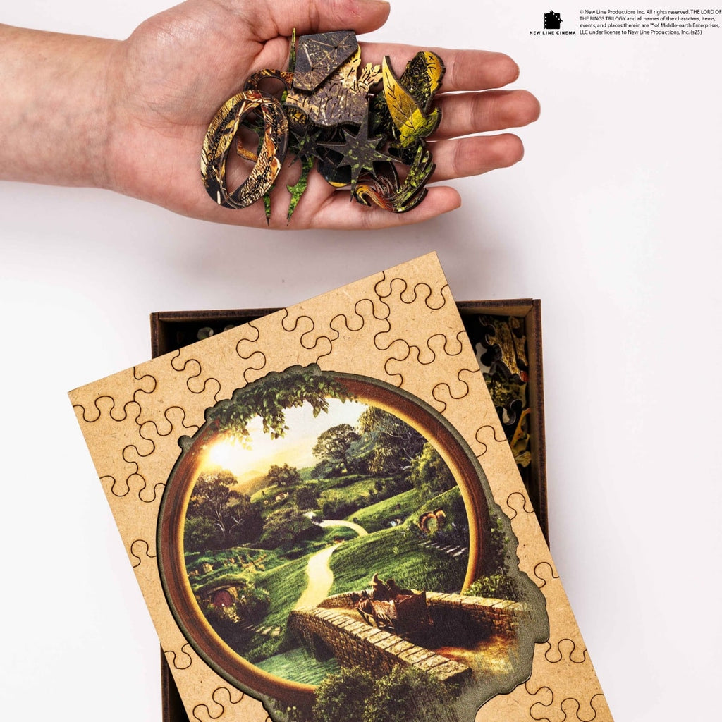 Hand holding puzzle pieces with a completed puzzle of a scenic landscape on a white background