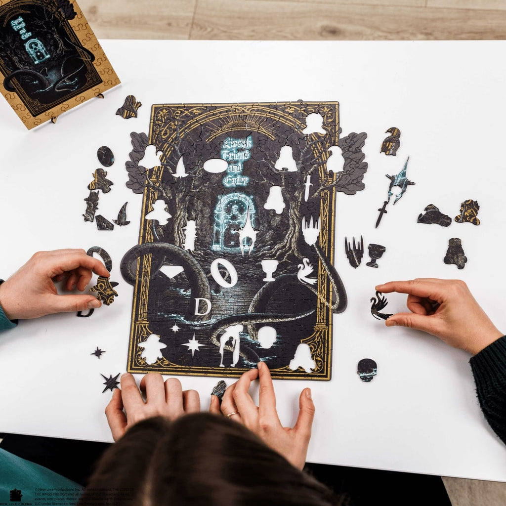 Two people assembling a puzzle with decorative pieces on a white surface.