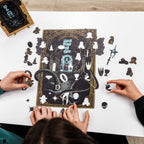Two people assembling a puzzle with decorative pieces on a white surface.