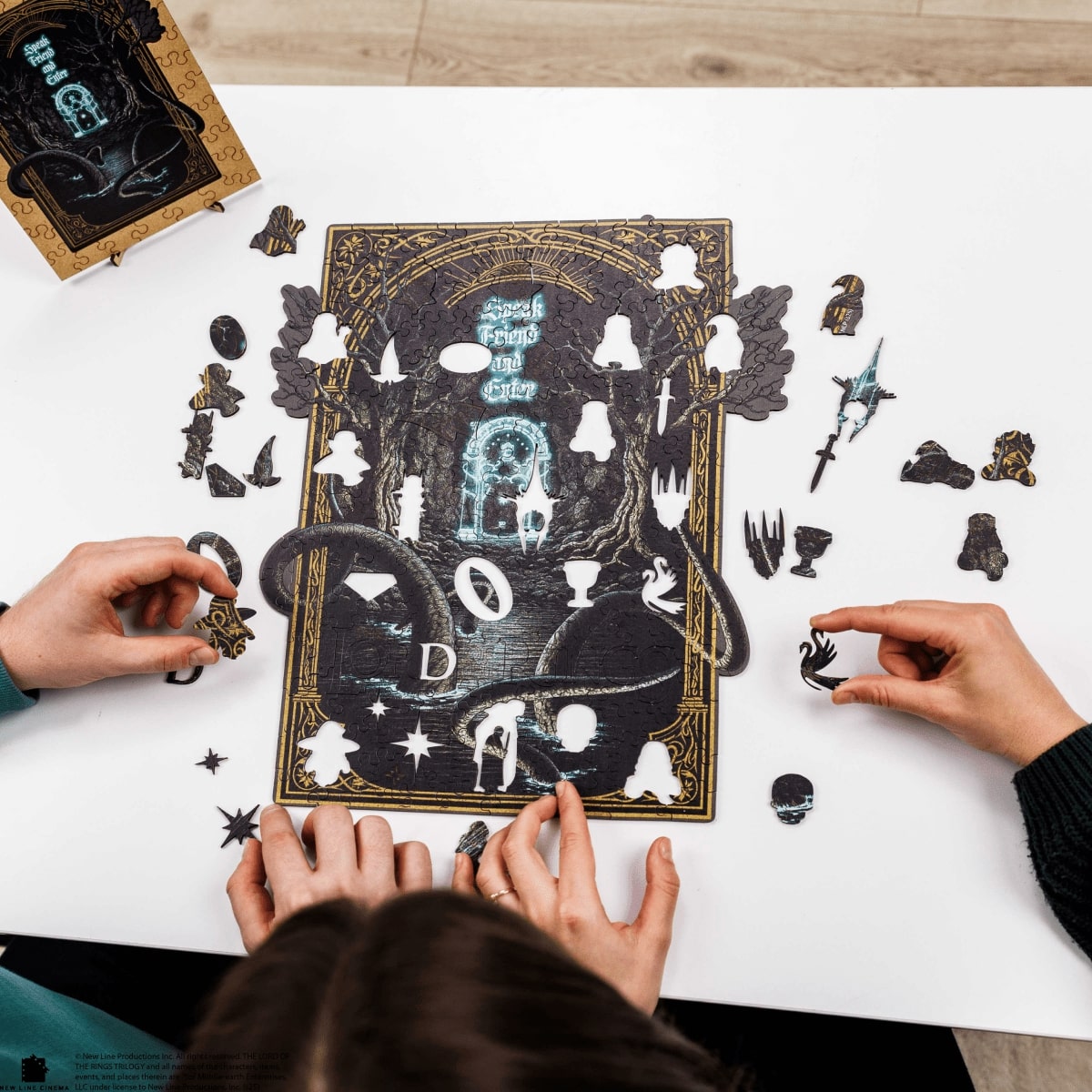 Two people assembling a puzzle with decorative pieces on a white surface.