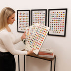 Woman holding a world map with flags, framed maps on the wall.