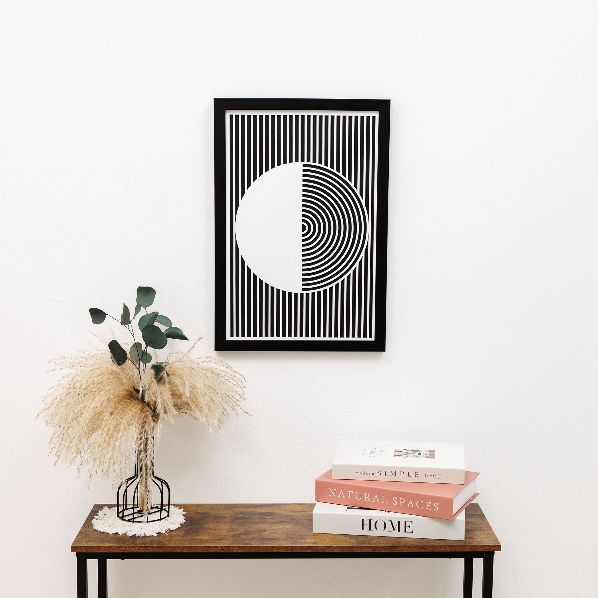 Framed geometric art piece on a wall above a wooden table with decor items.