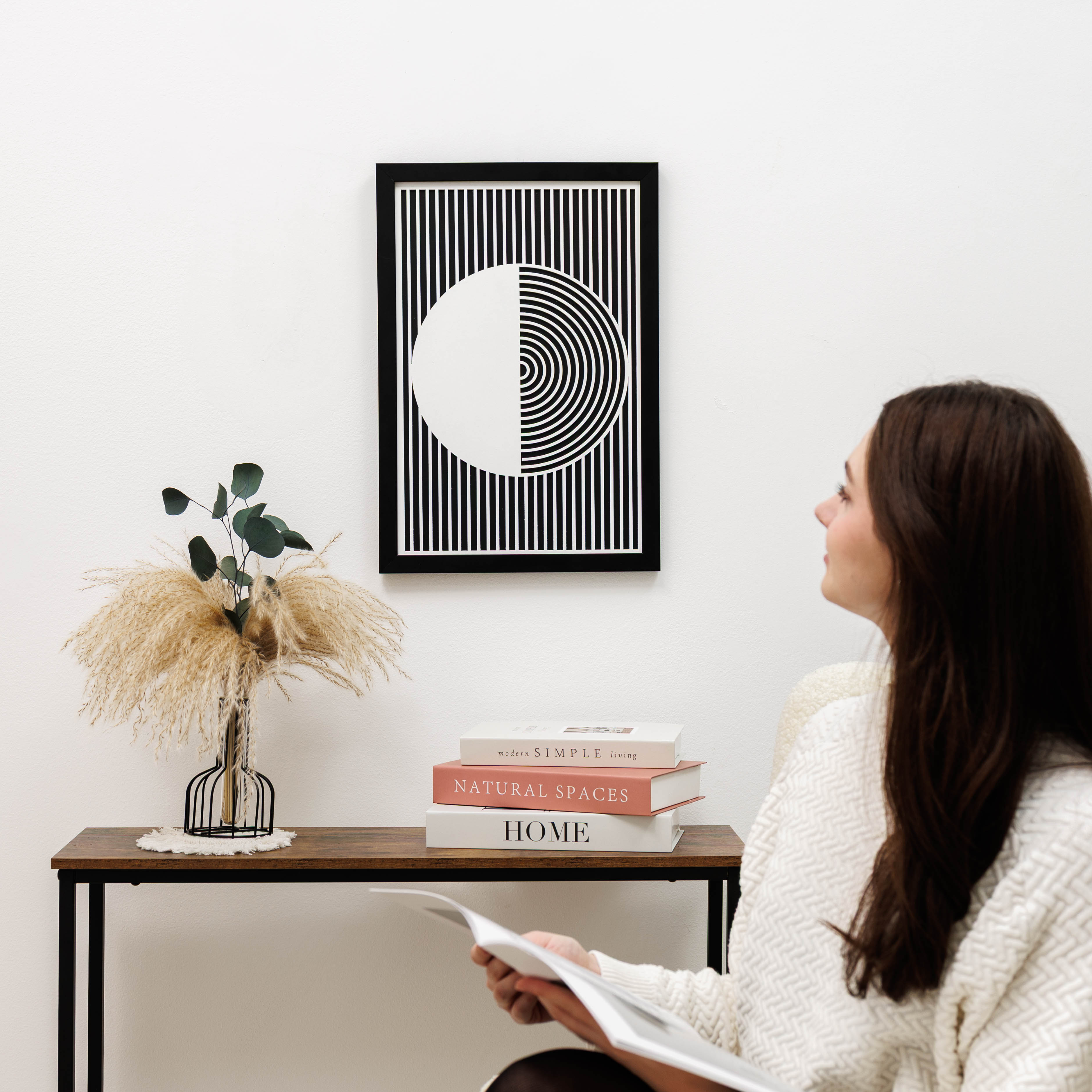 Woman sitting in a room with a modern abstract art piece on the wall.