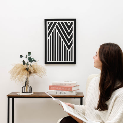 Woman reading a book in a cozy room with a geometric art piece on the wall.