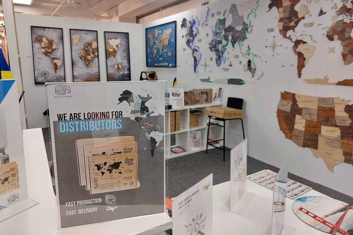 Exhibition stand with world maps and promotional materials on a table.
