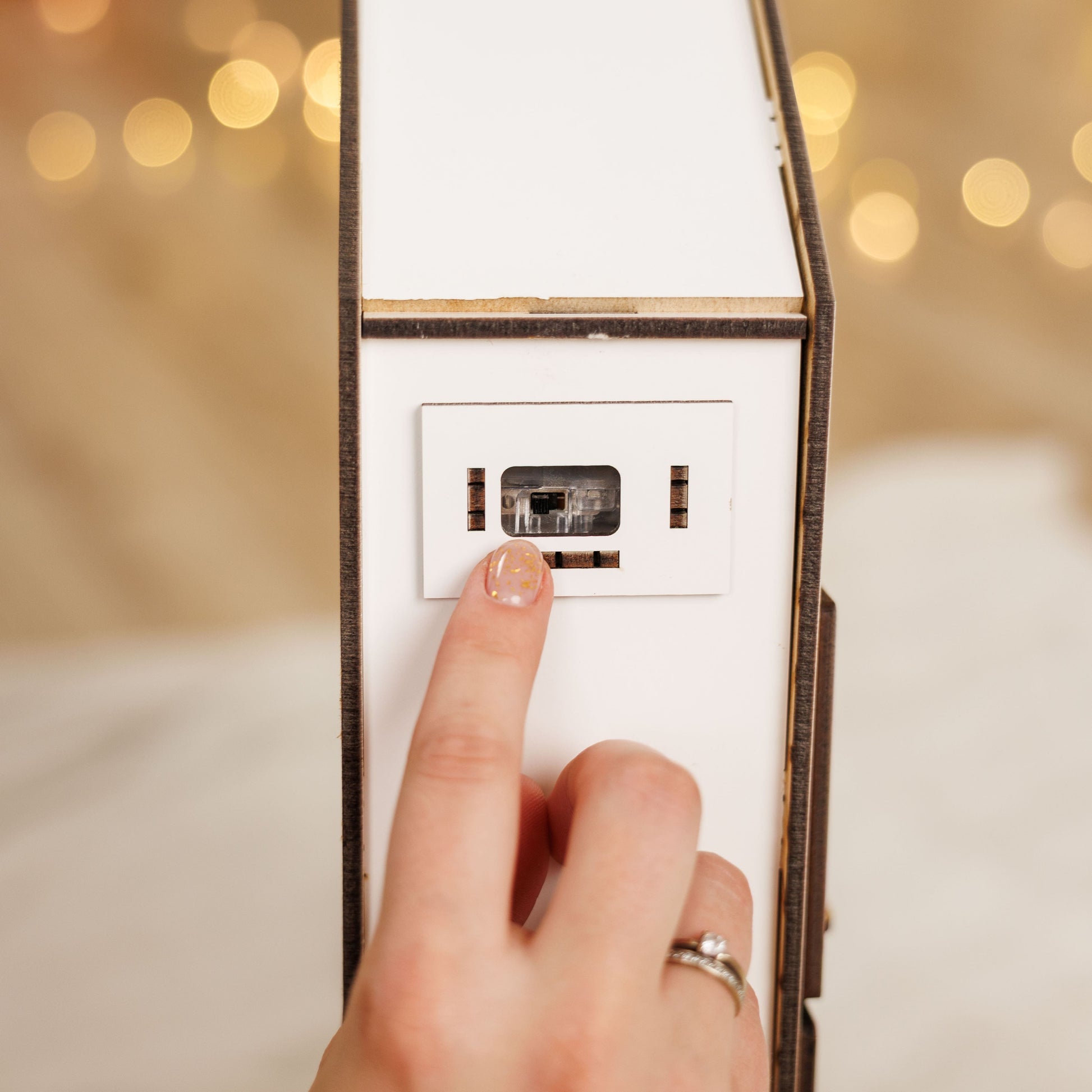 Hand pressing a light switch with blurred lights in the background