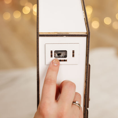 Hand pressing a light switch with blurred lights in the background