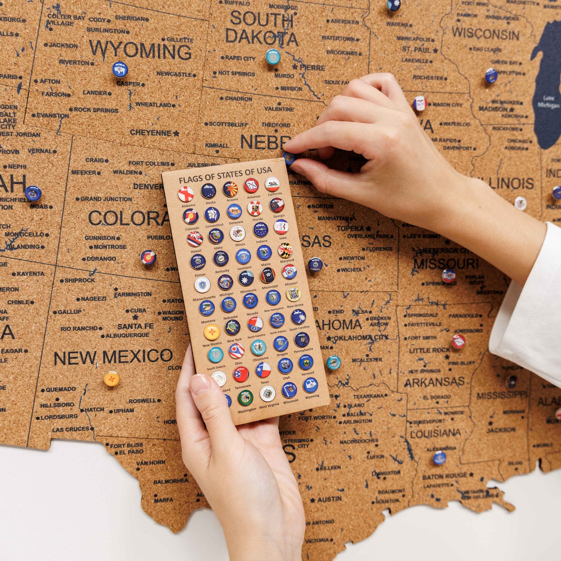 Person holding a card with small flags over a map of the United States.