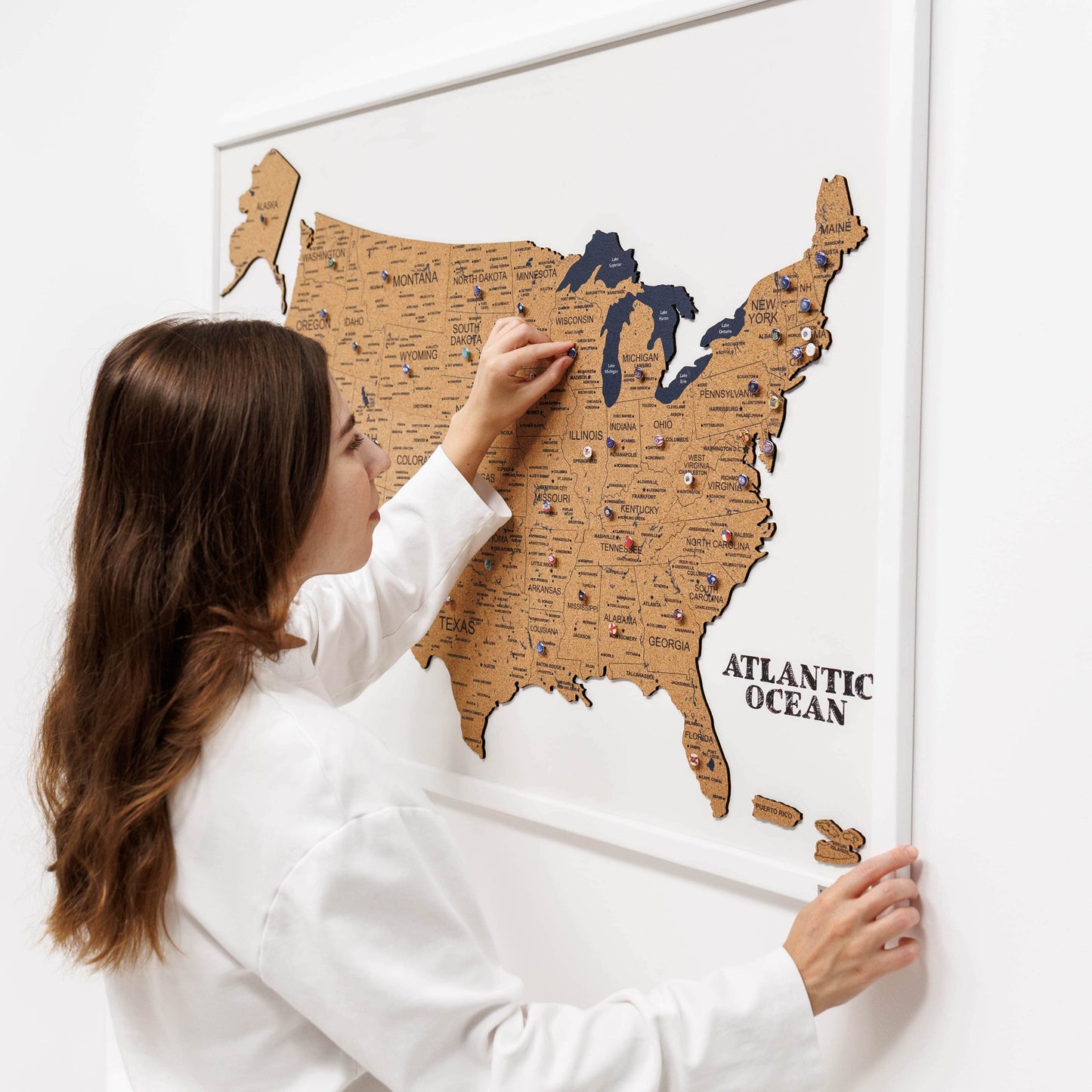 Woman scratching a map of the United States on a white wall
