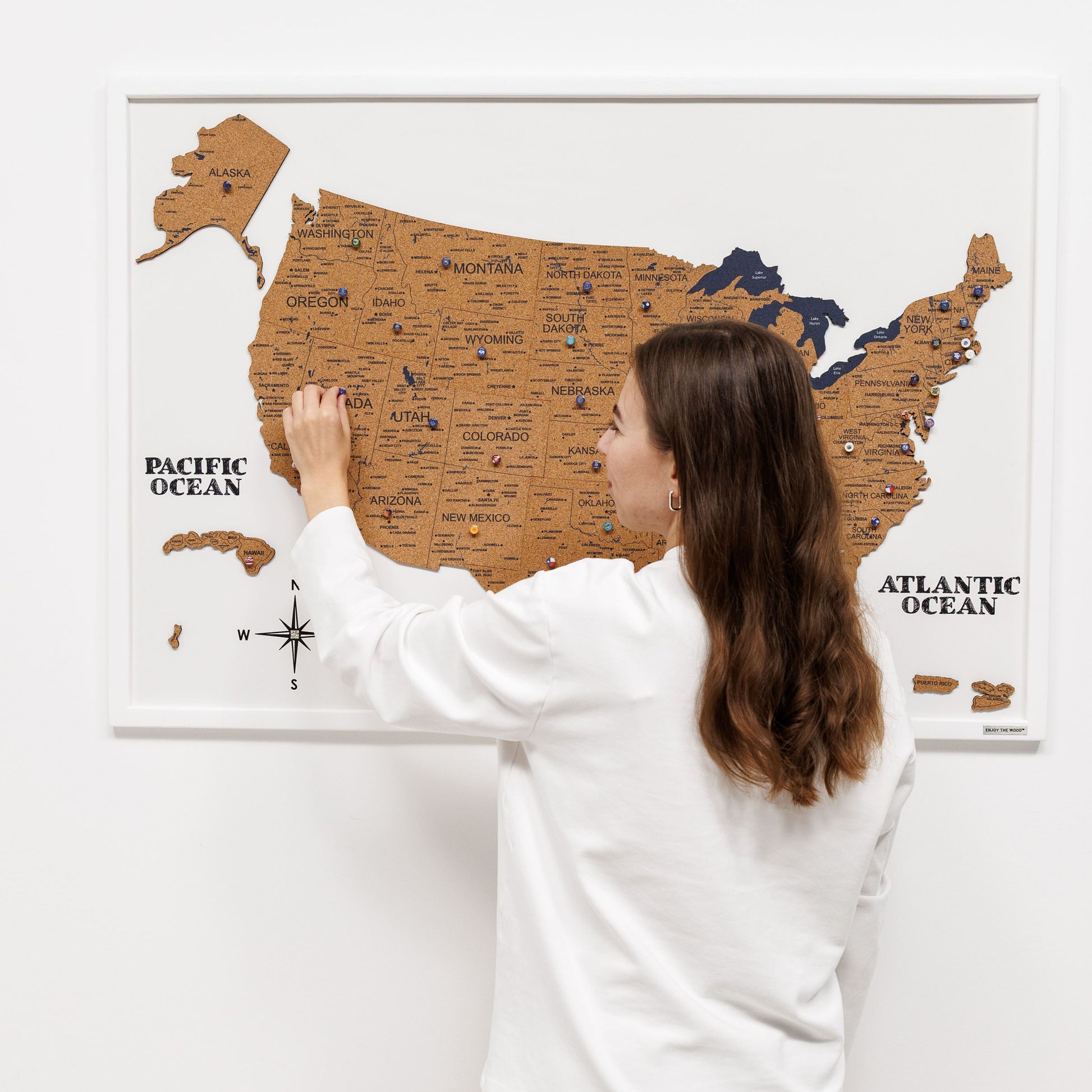 Woman interacting with a wooden map of the United States on a white wall