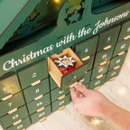 Advent calendar with 'Christmas with the Johnsons' text, hand opening a drawer.