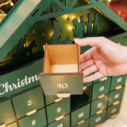 Hand opening a drawer in a Christmas-themed advent calendar