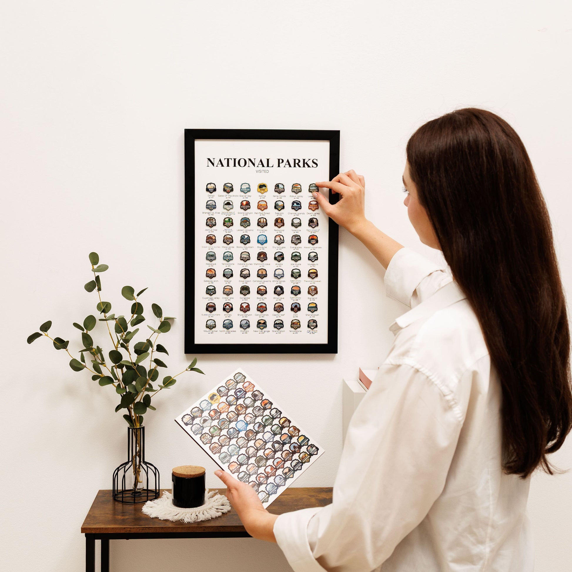 Woman hanging a framed print of national parks on a wall