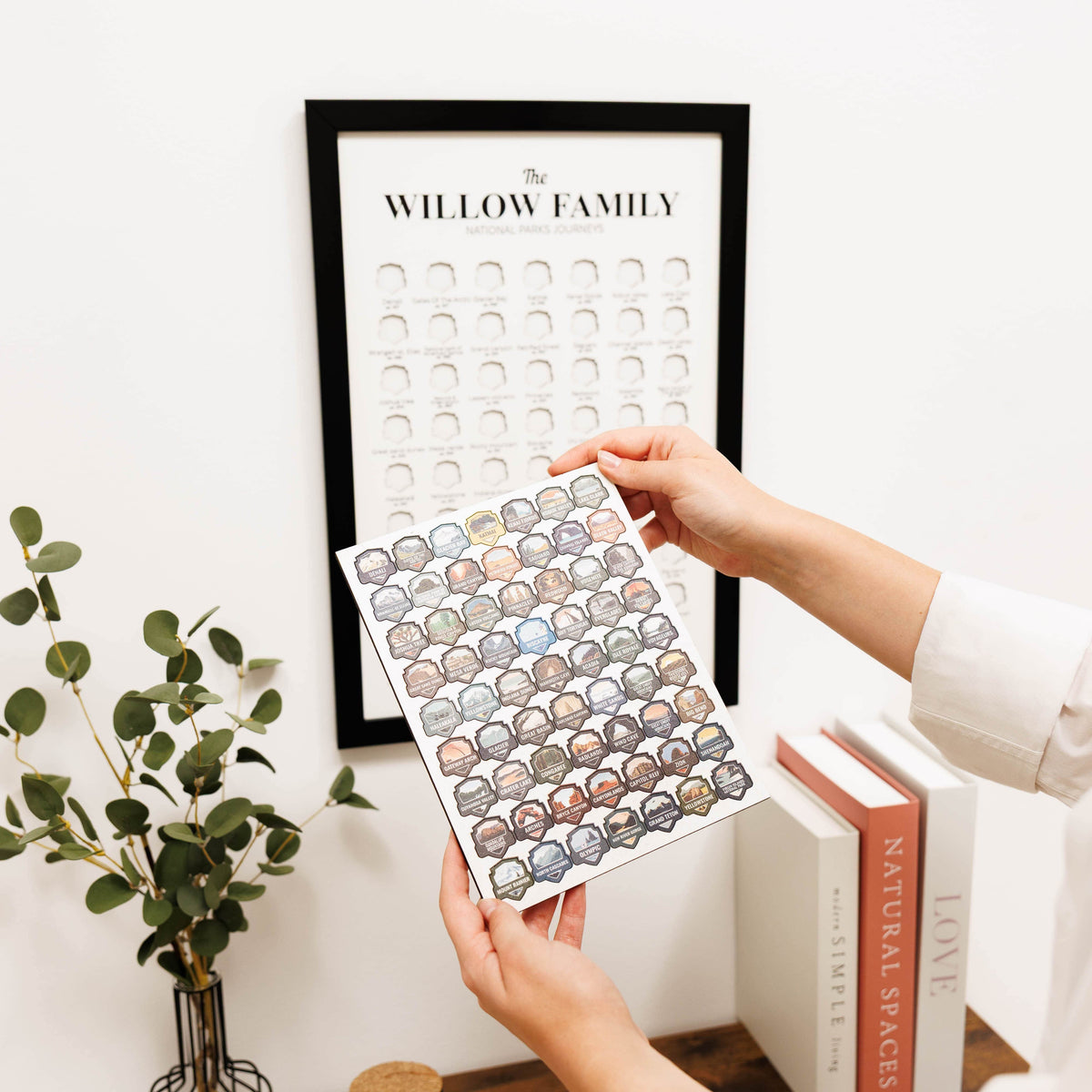 Person holding a personalized family tree chart with a framed version in the background.