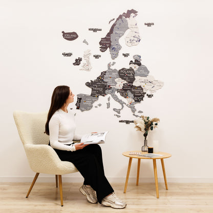 Woman sitting in a chair in front of a large wall map of Europe.