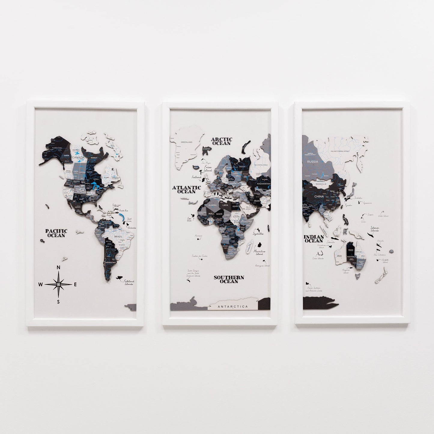 Three framed world maps on a white wall