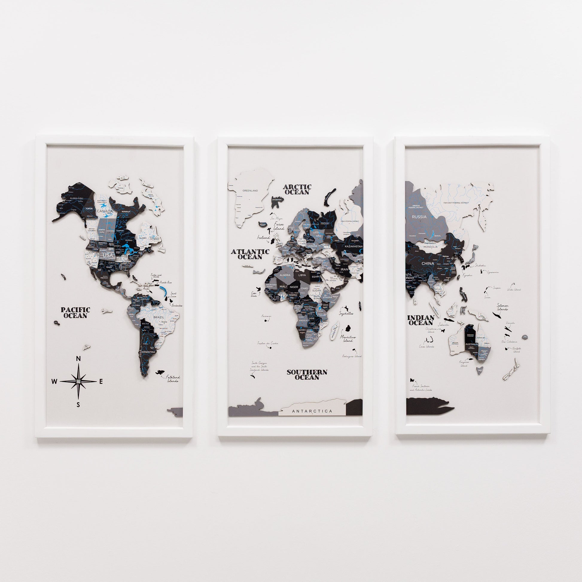 Three framed world maps on a white wall