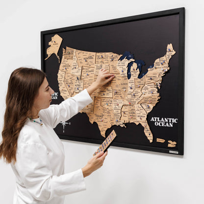 Woman interacting with a wooden map of the United States on a wall