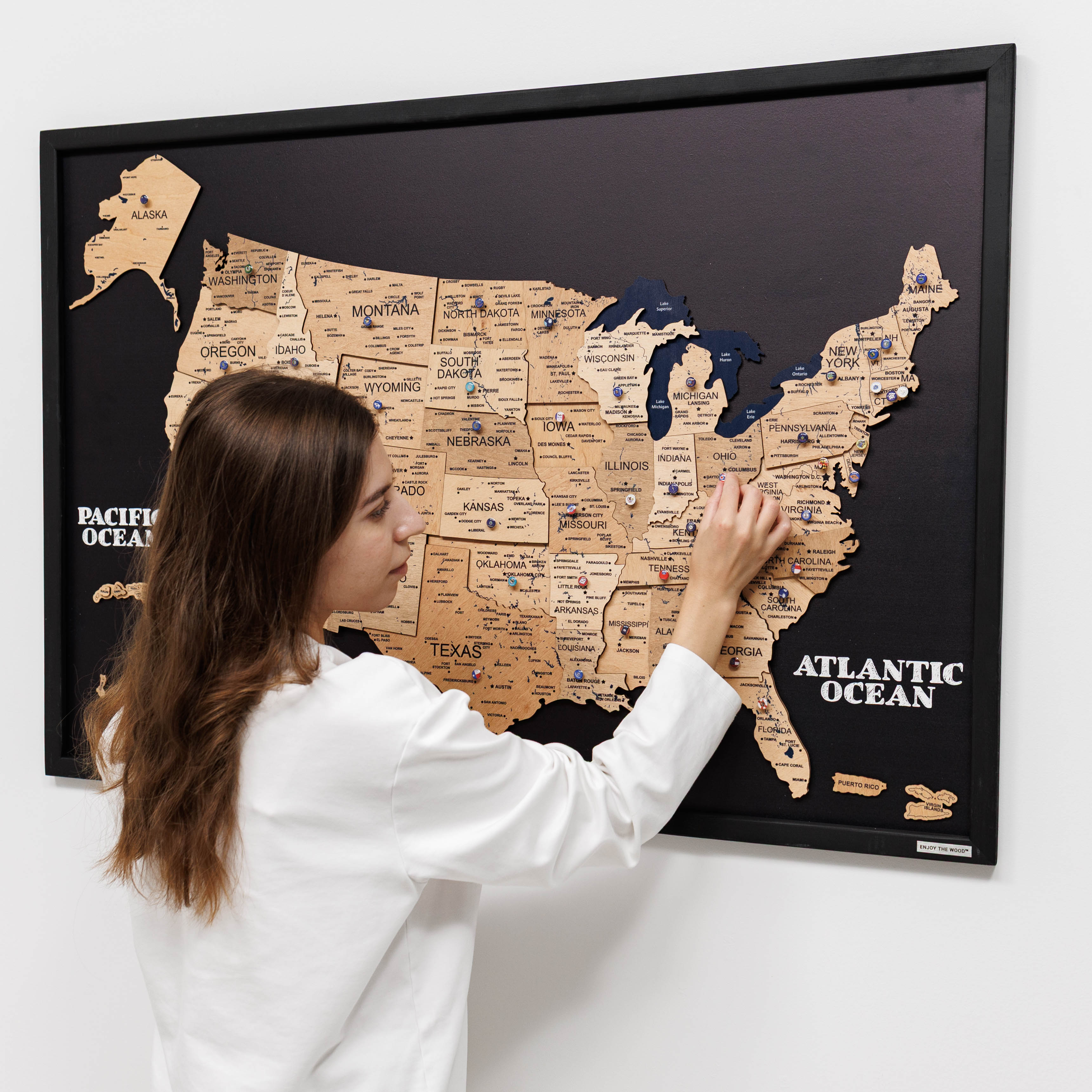 Woman interacting with a framed map of the United States on a wall