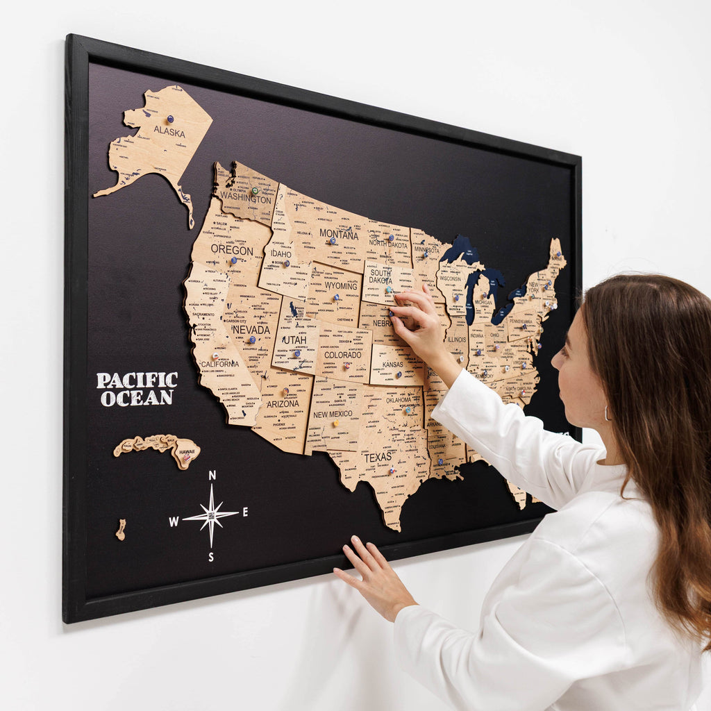 Woman interacting with a framed map of the United States on a white wall