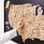 Map of the United States with pins marking locations, held by a person.