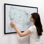 Woman interacting with a framed map of the United States on a white wall