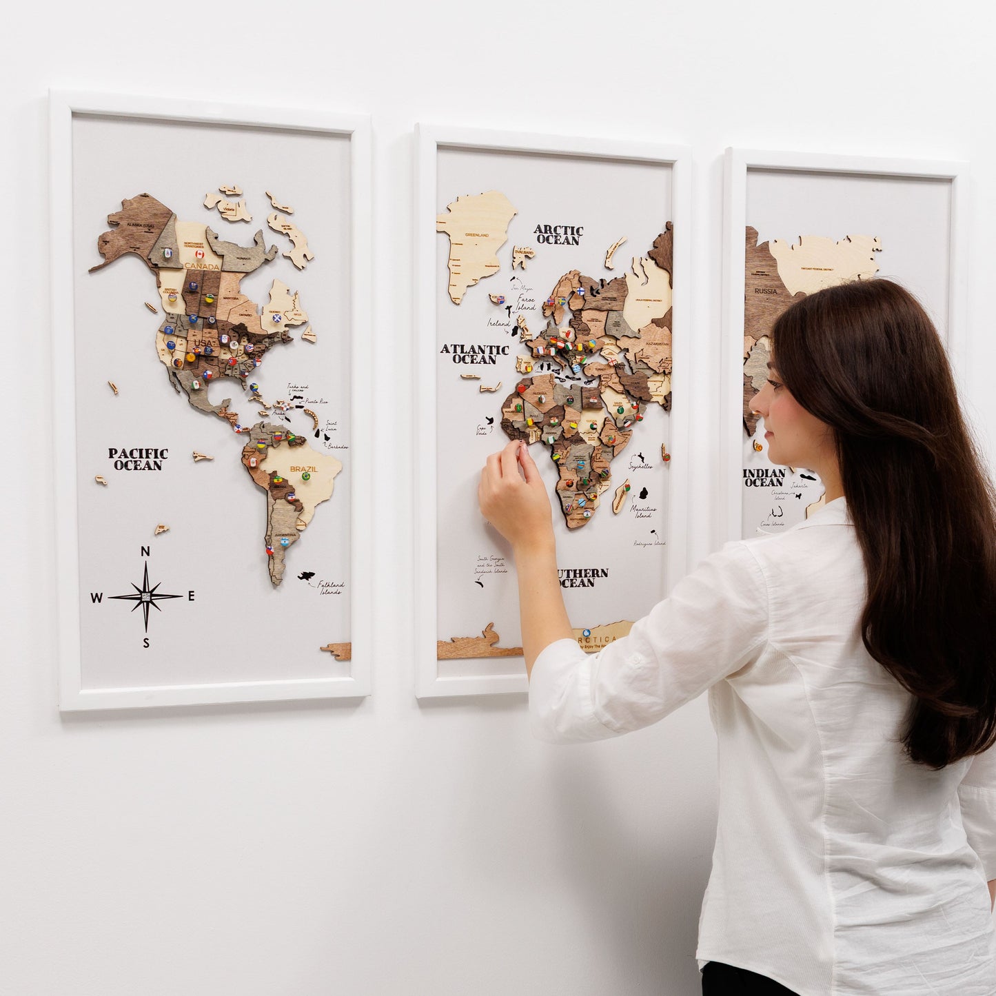 Woman interacting with a wooden world map on a wall
