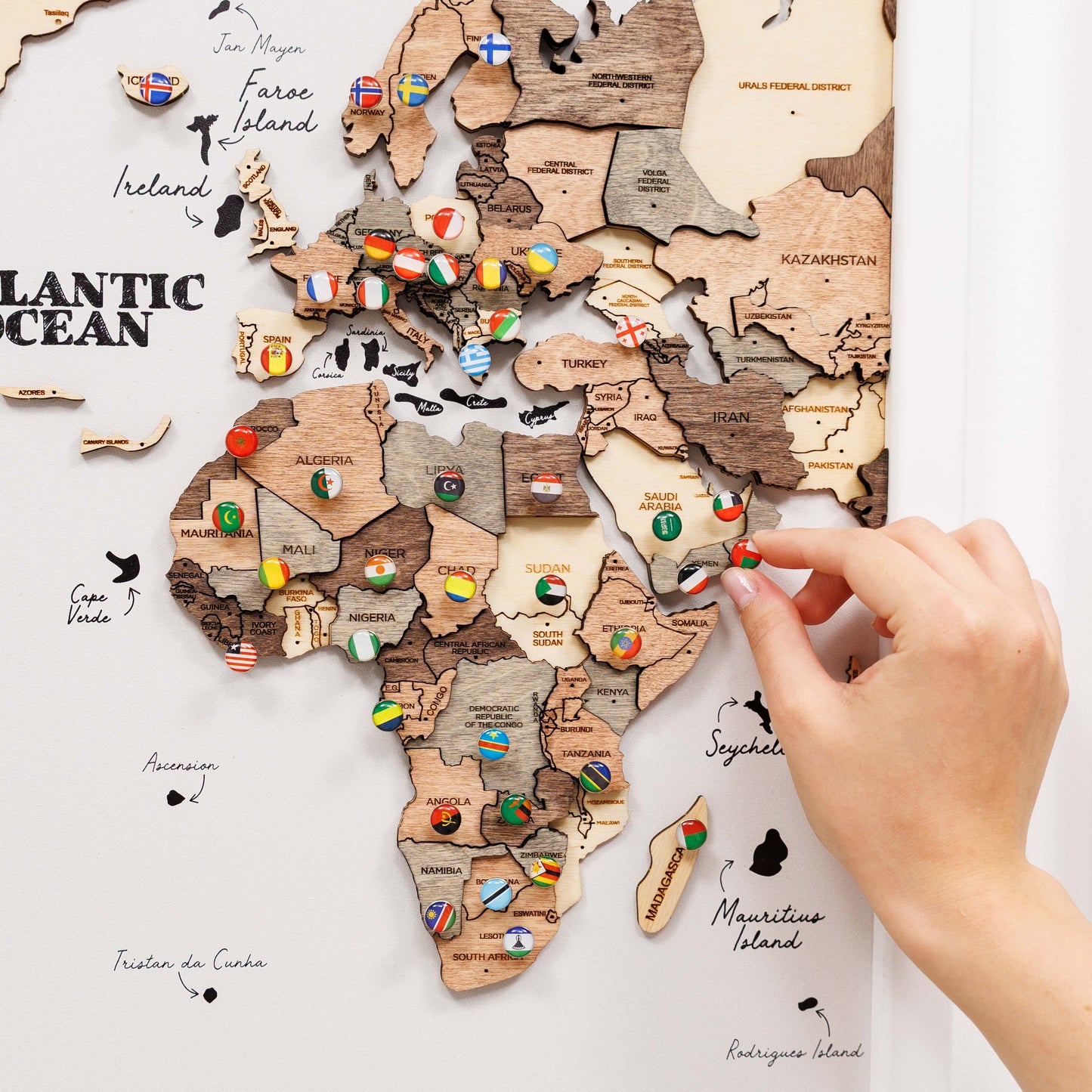 Wooden world map with flags and a hand interacting with it