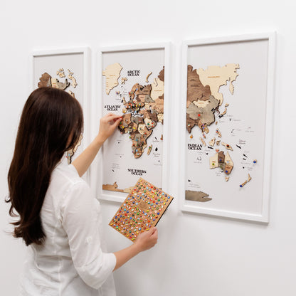 Woman interacting with a wooden world map on a white wall