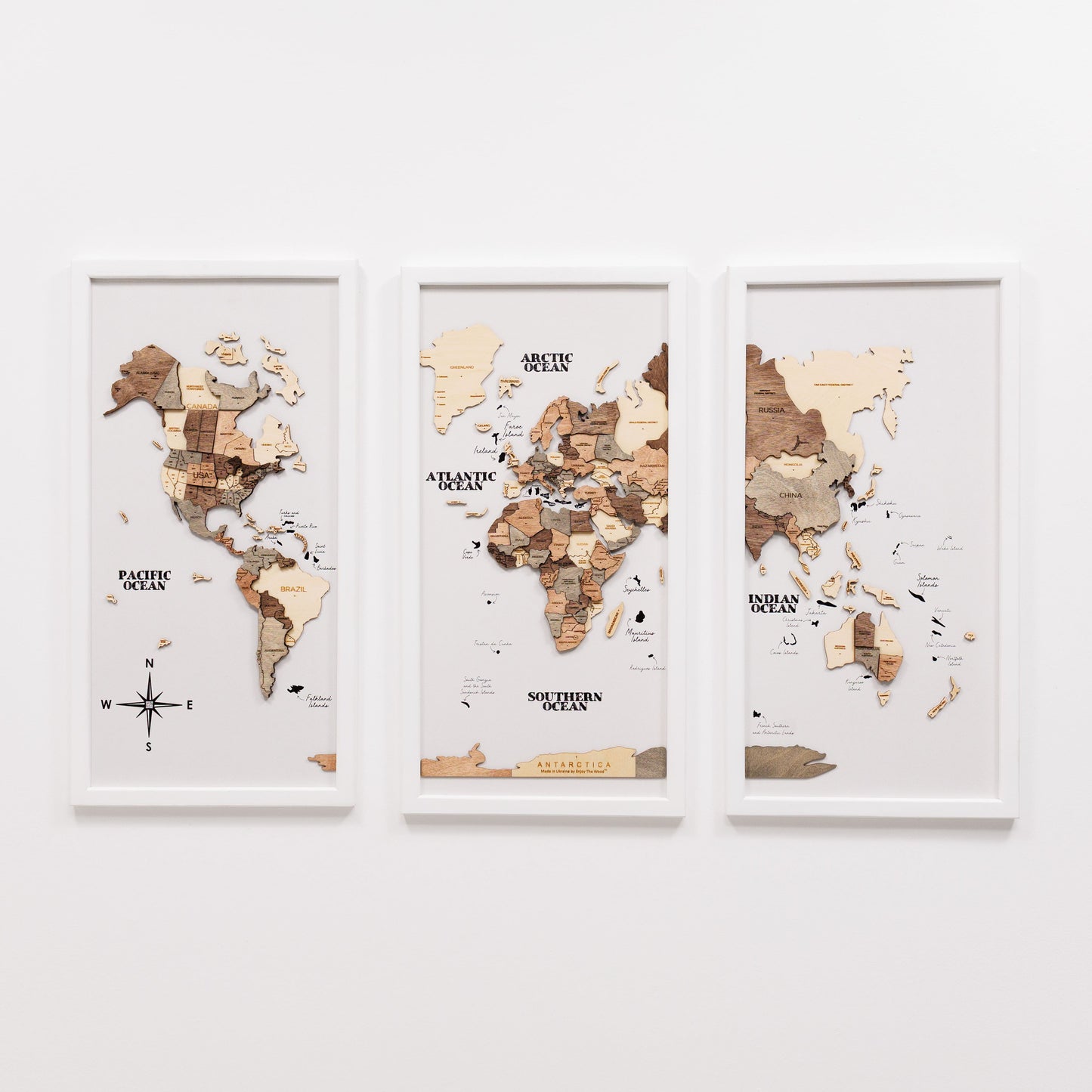 Three framed world maps on a white wall