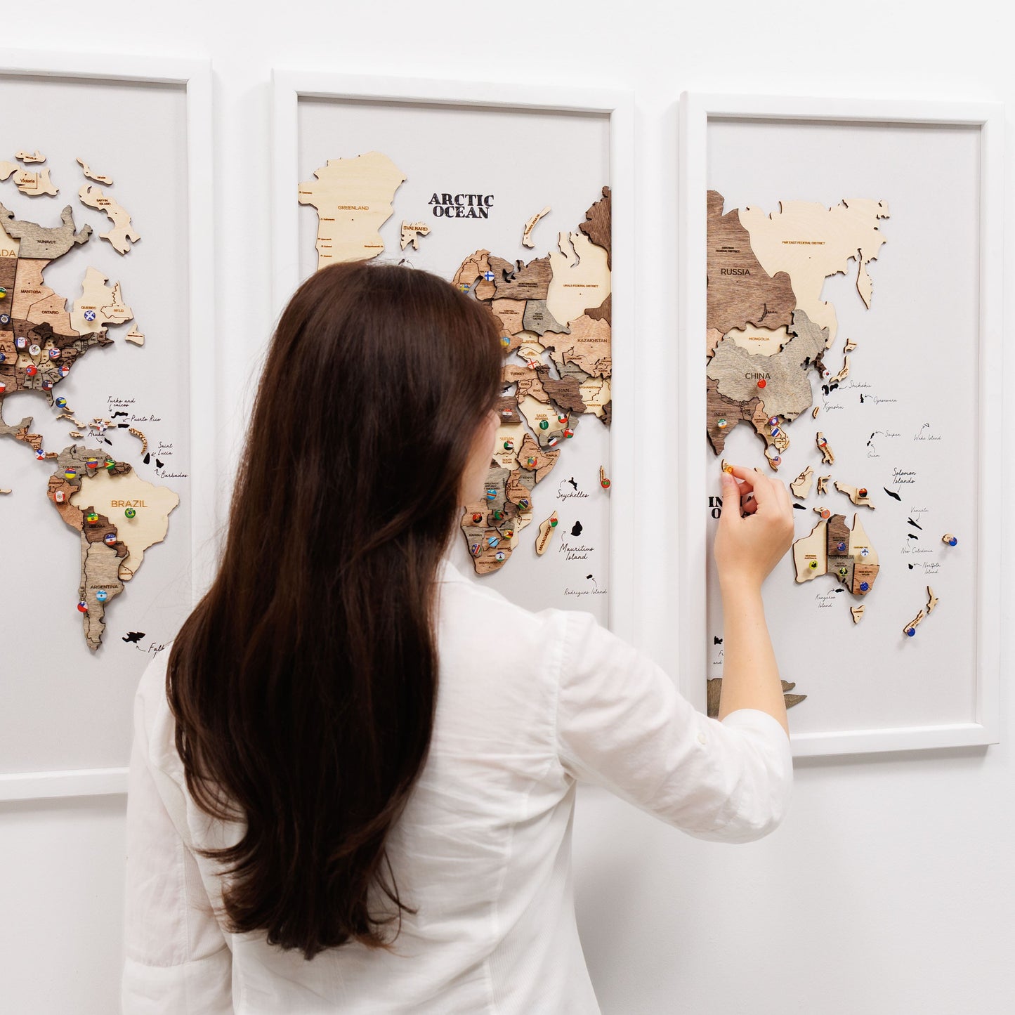 Woman interacting with a wooden world map on a wall
