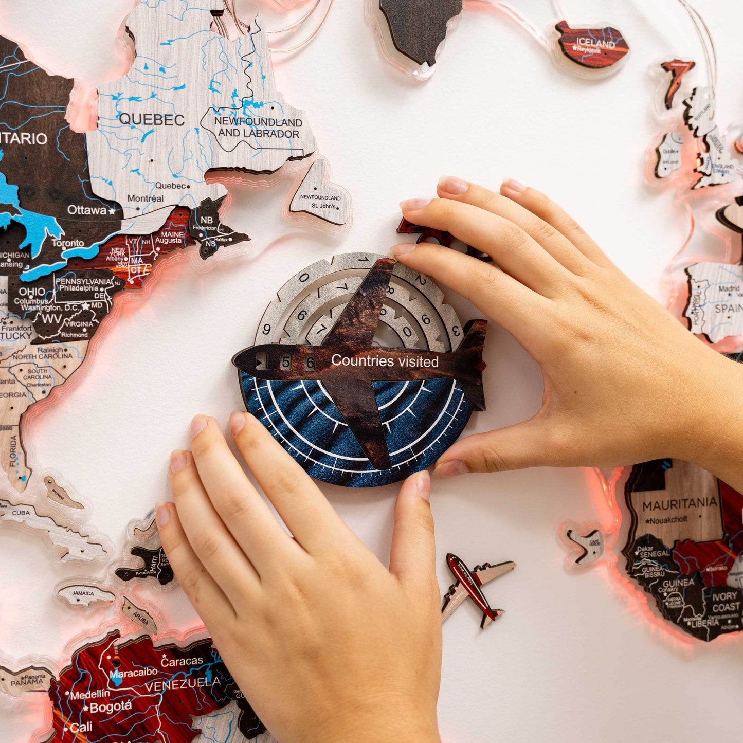 Hands arranging a world map puzzle on a white surface
