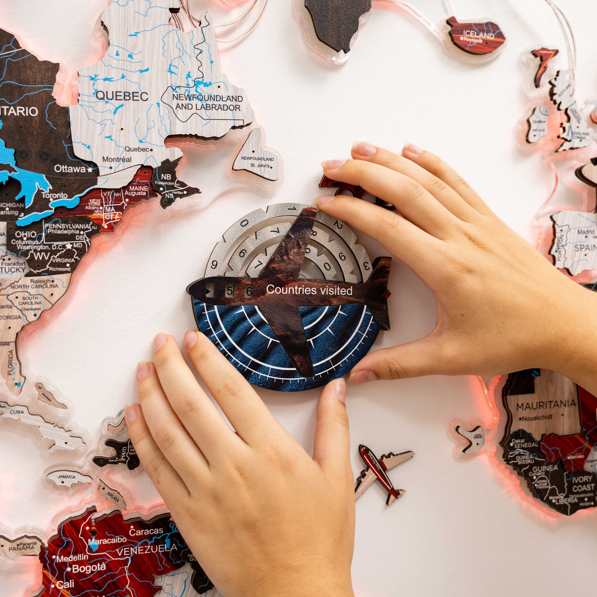 Hands arranging a world map puzzle on a white surface