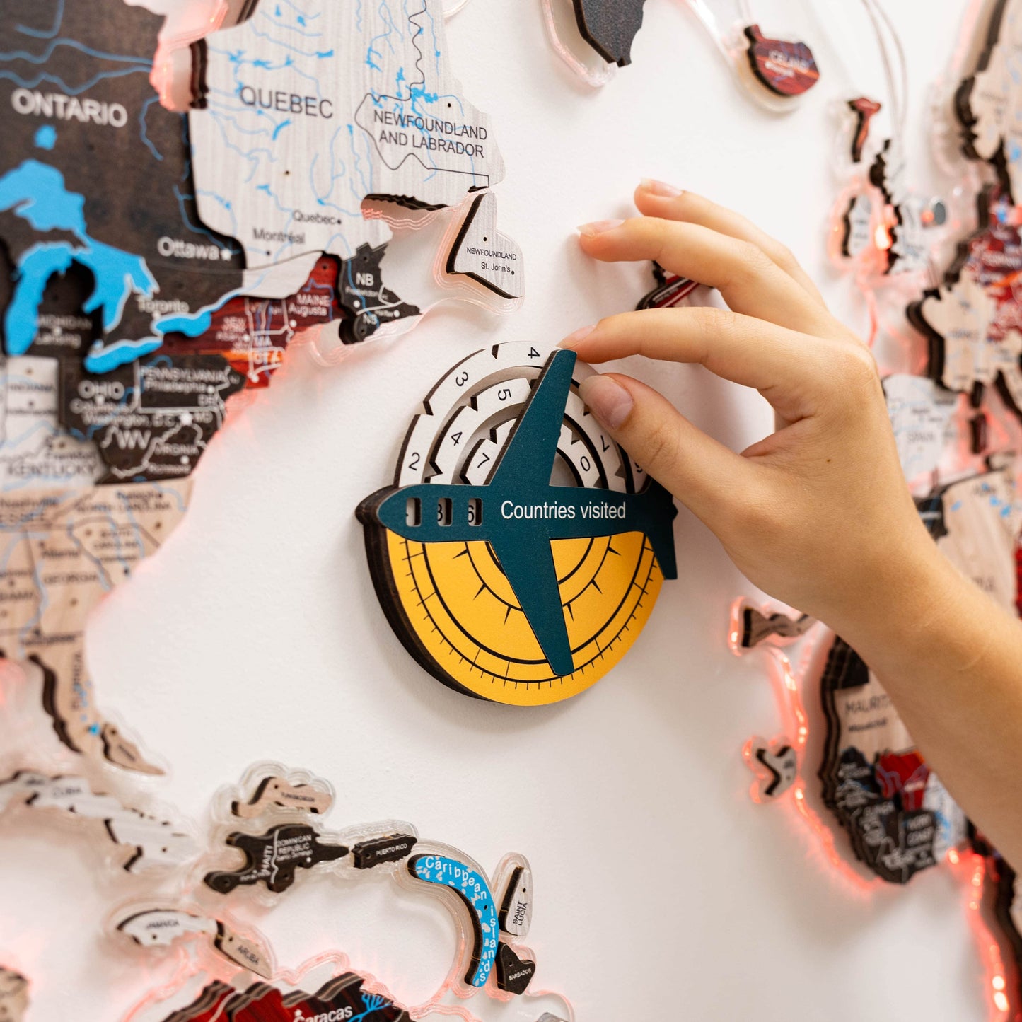 Hand placing a 'Countries visited' badge on a world map with decorative lights.