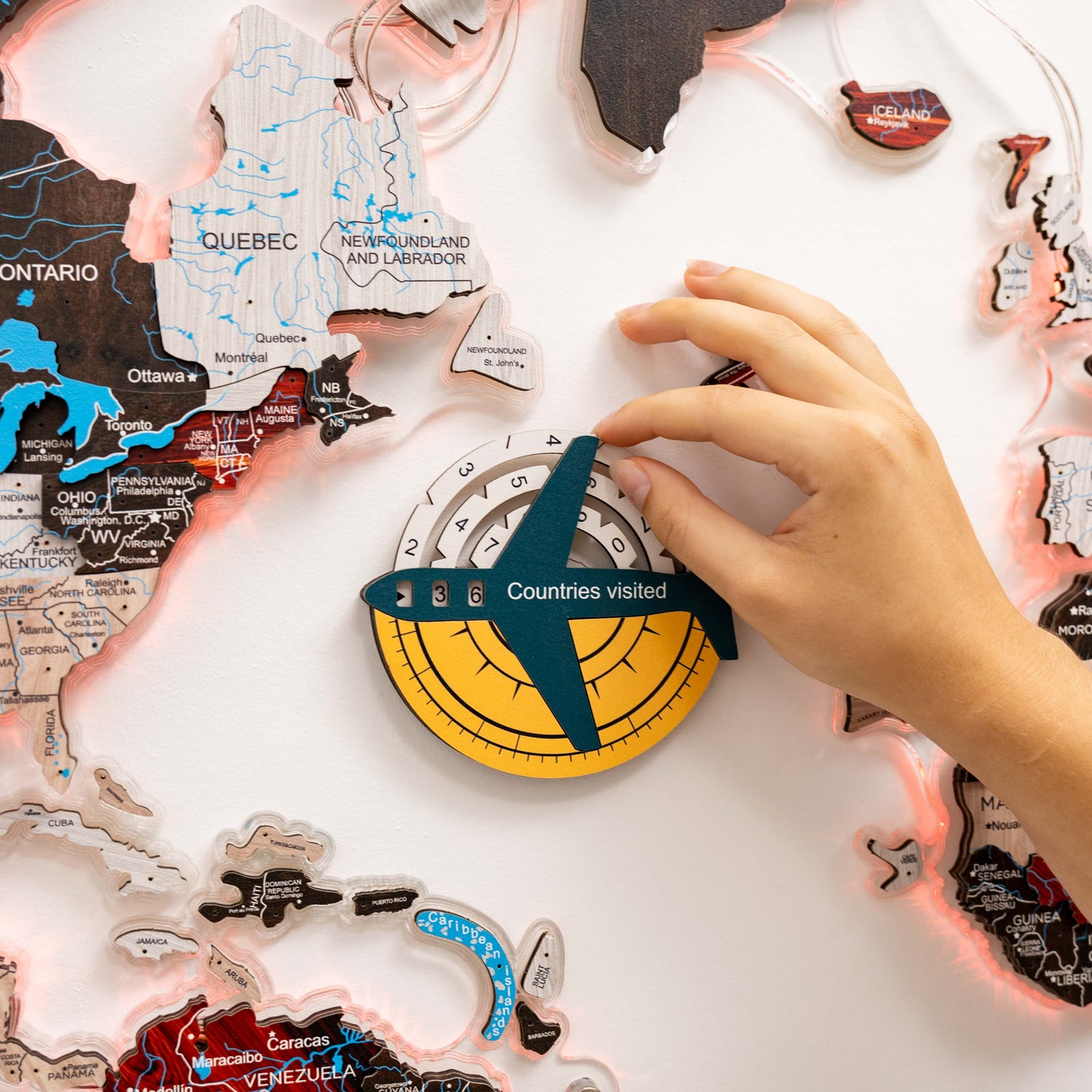 Map of Canada with a hand placing a travel ornament on a 'Countries visited' display.