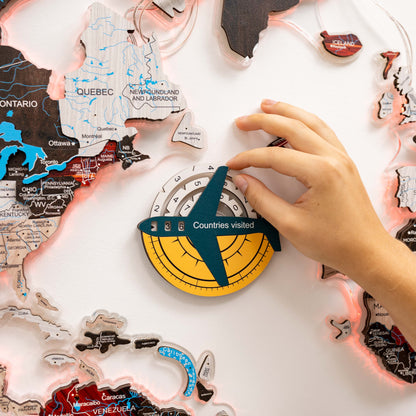 Map of Canada with a hand placing a travel ornament on a 'Countries visited' display.