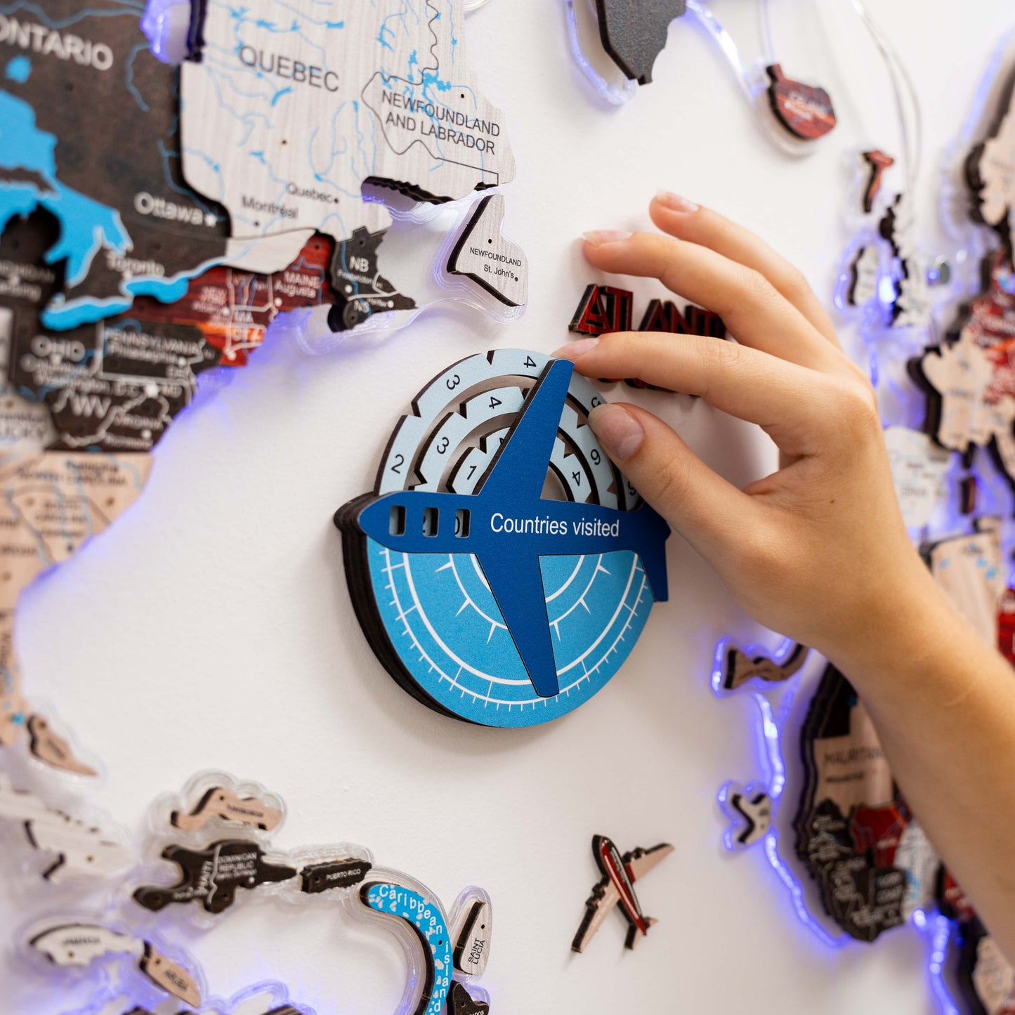 Map with a hand placing a blue airplane sticker labeled 'Countries visited' on a world map.