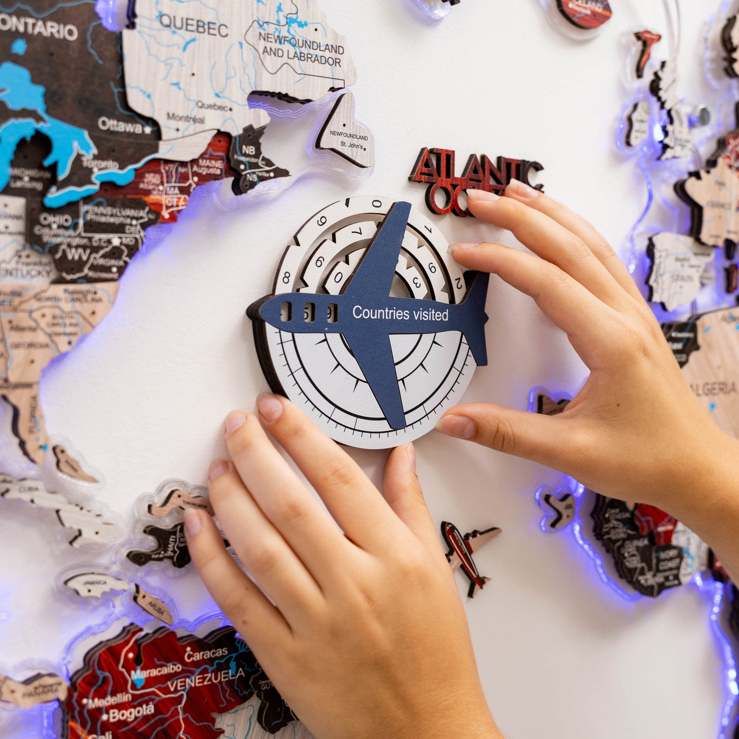 Person interacting with a travel-themed board game or poster, featuring a compass and airplane icon.