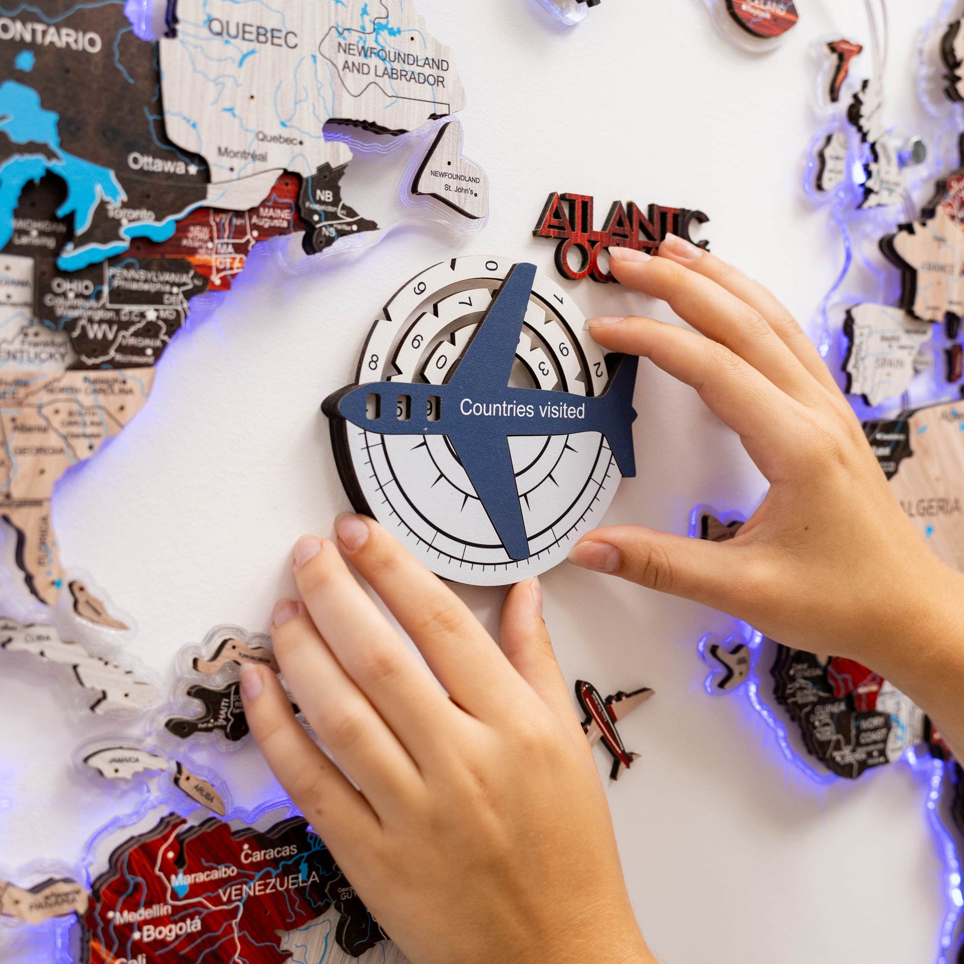 Person interacting with a travel-themed board game or poster, featuring a compass and airplane icon.