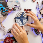 Person interacting with a travel-themed board game or poster, featuring a compass and airplane icon.