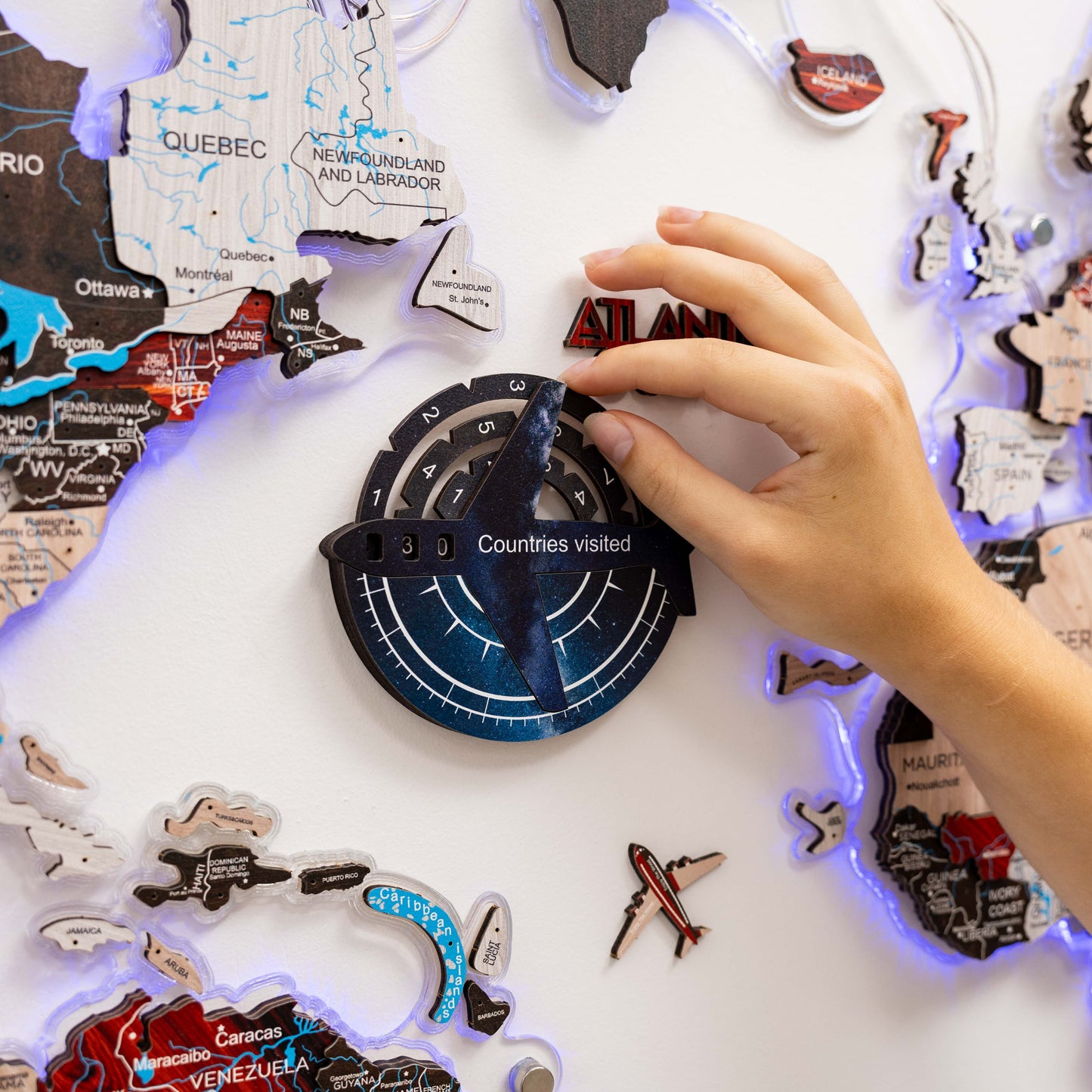 Hand interacting with a travel-themed decorative item featuring world map and travel stickers.