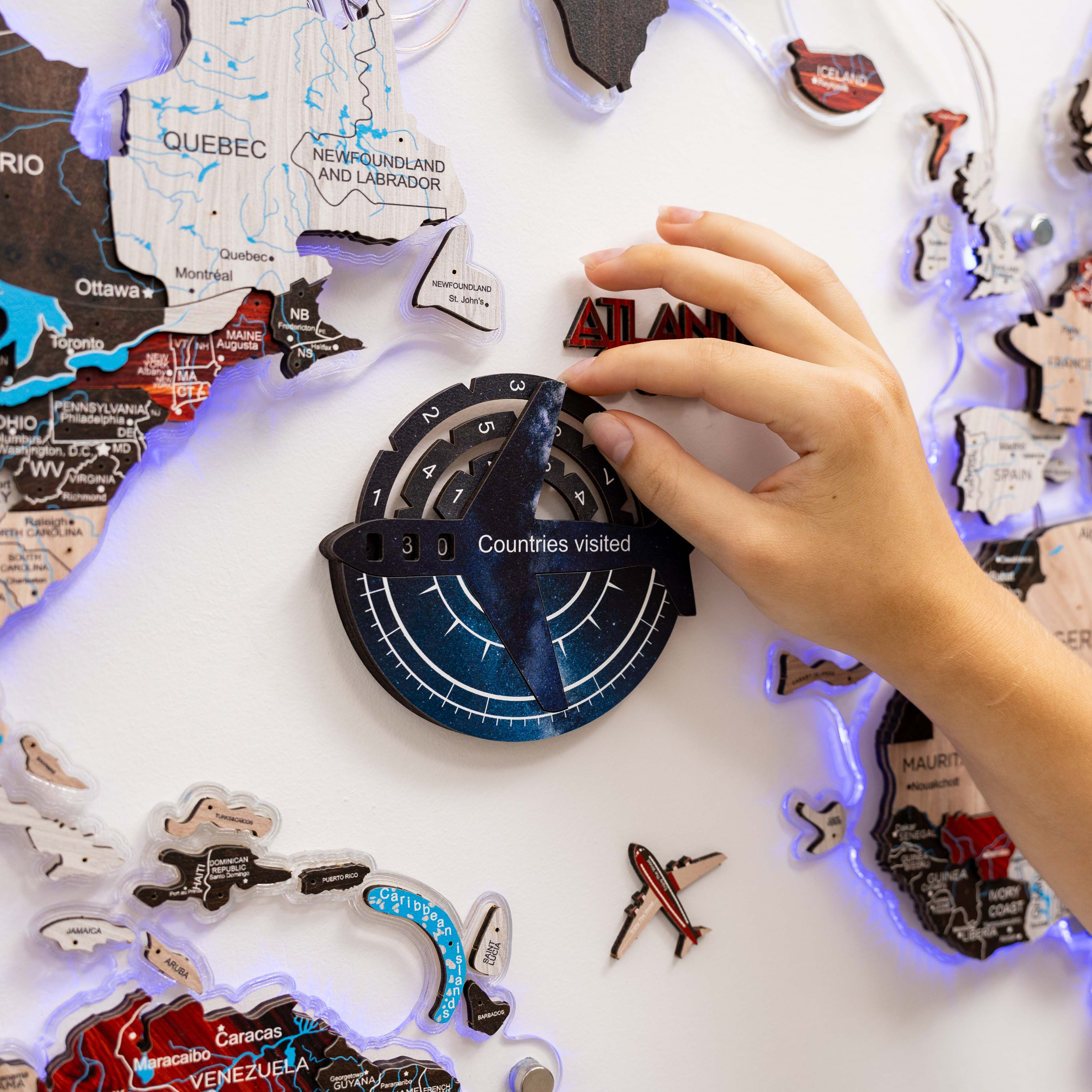 Hand interacting with a travel-themed decorative item featuring world map and travel stickers.