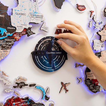 Hand interacting with a travel-themed decorative item featuring world map and travel stickers.