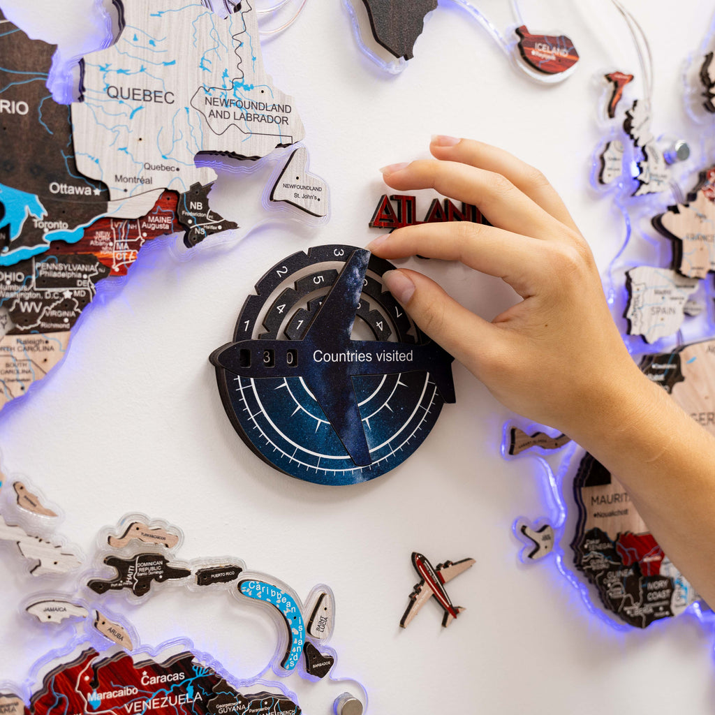 Hand interacting with a travel-themed decorative item featuring world map and travel stickers.